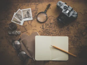 A notebook, camera, power glasses, and a magnifying glass arranged on a vintage map background.