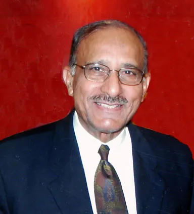 A Pakistani man in a suit and tie smiling warmly at the camera